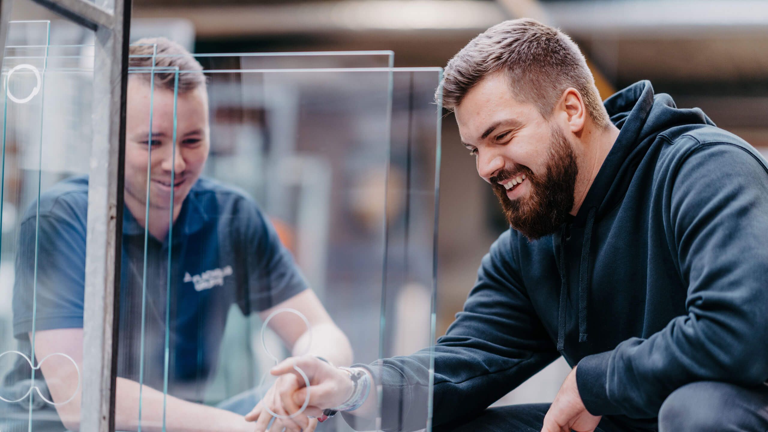 Zwei Arbeiter der Flachglas Gruppe vor einer Glasscheibe